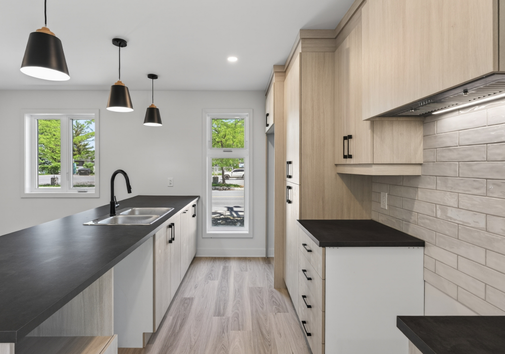Cuisine aux armoires de bois et comptoir noir d’un logement locatif à Salaberry-de-Valleyfield